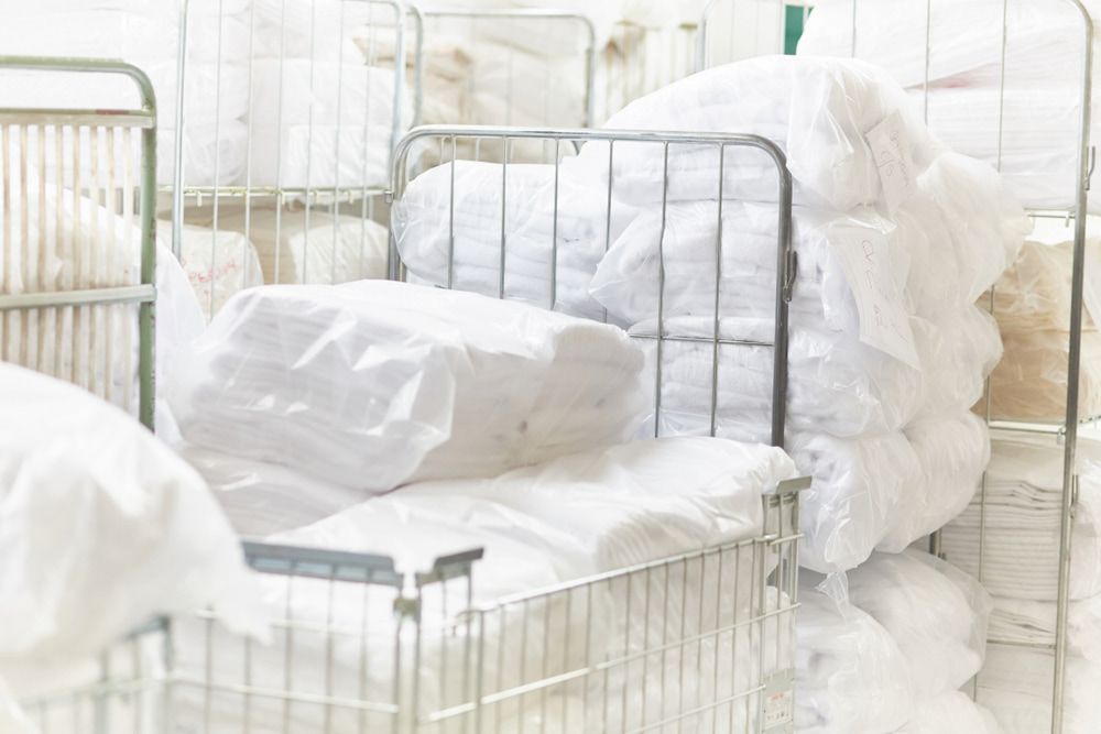 A Bunch Of White Sheets Are Stacked On Top Of Each Other In A Laundromat — Macquarie Dry Cleaners In Dubbo, NSW