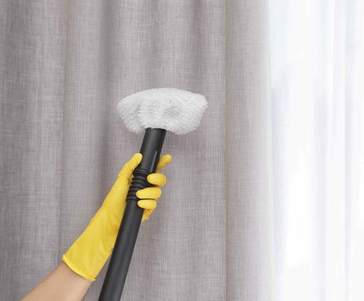 A Person Wearing Yellow Gloves Is Holding A Brush In Front Of A Curtain — Macquarie Dry Cleaners In Dubbo, NSW