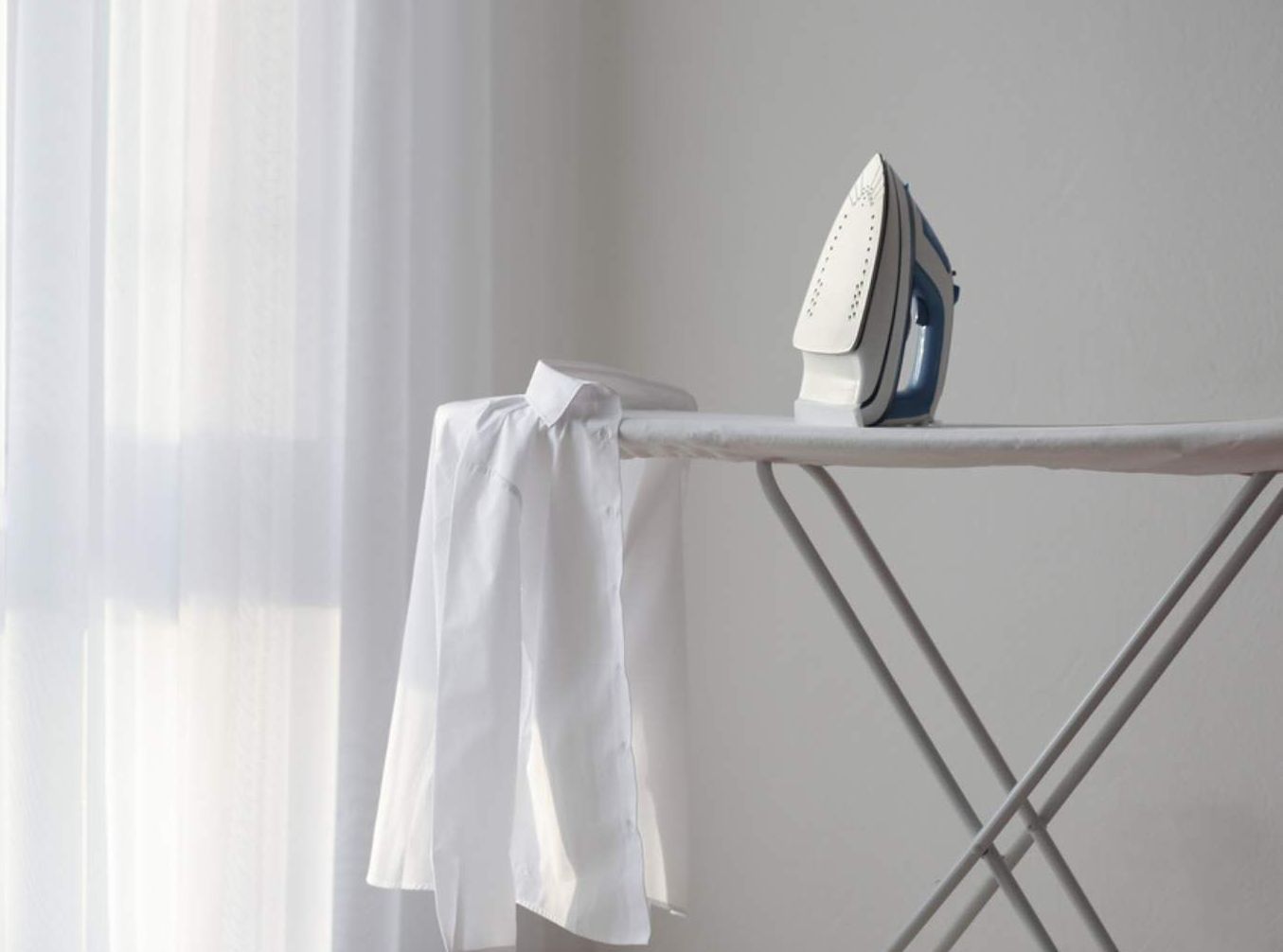 A White Shirt Is Sitting On An Ironing Board Next To An Iron — Macquarie Dry Cleaners In Dubbo, NSW