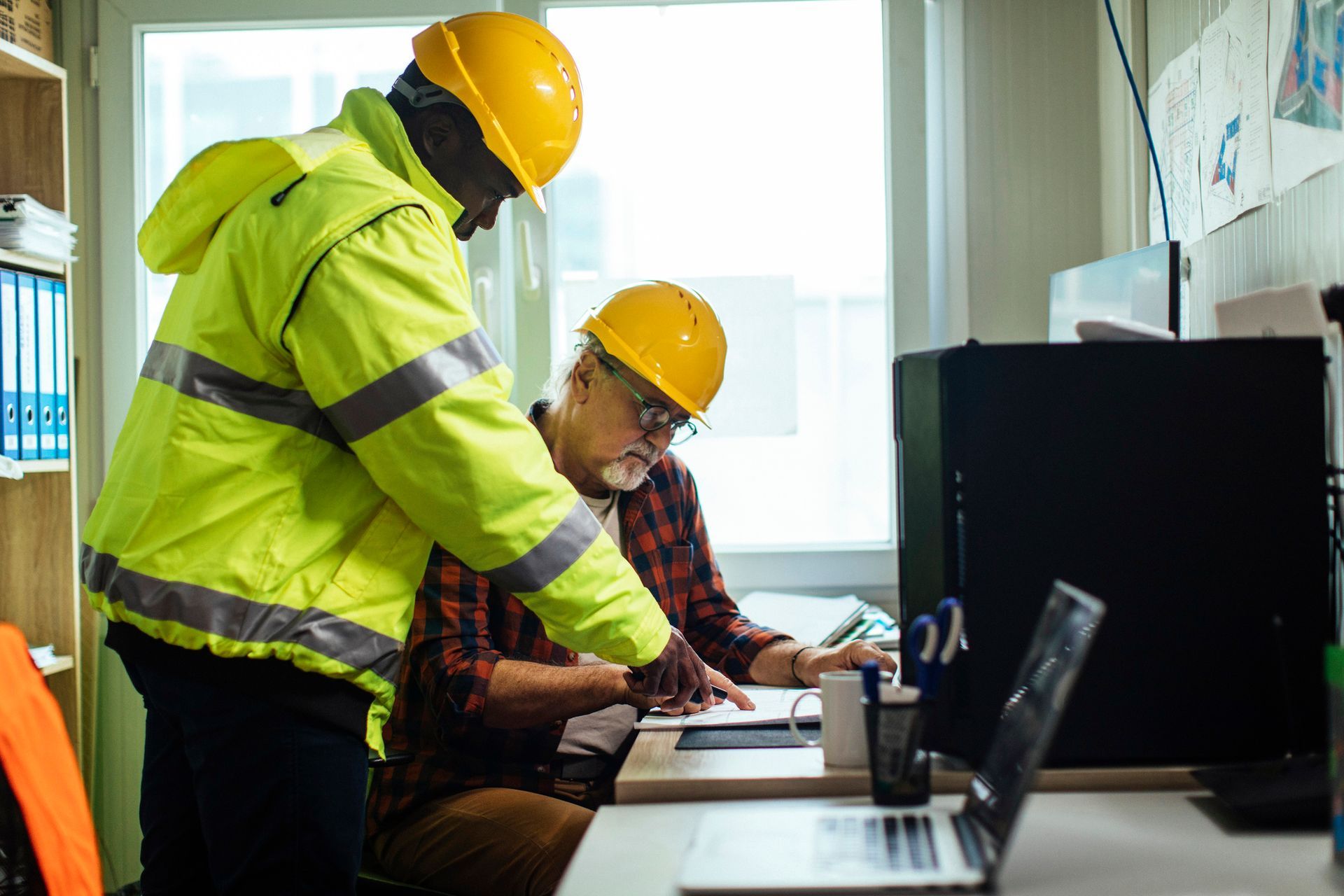 construction workers in a jobsite office going over a project on their computer