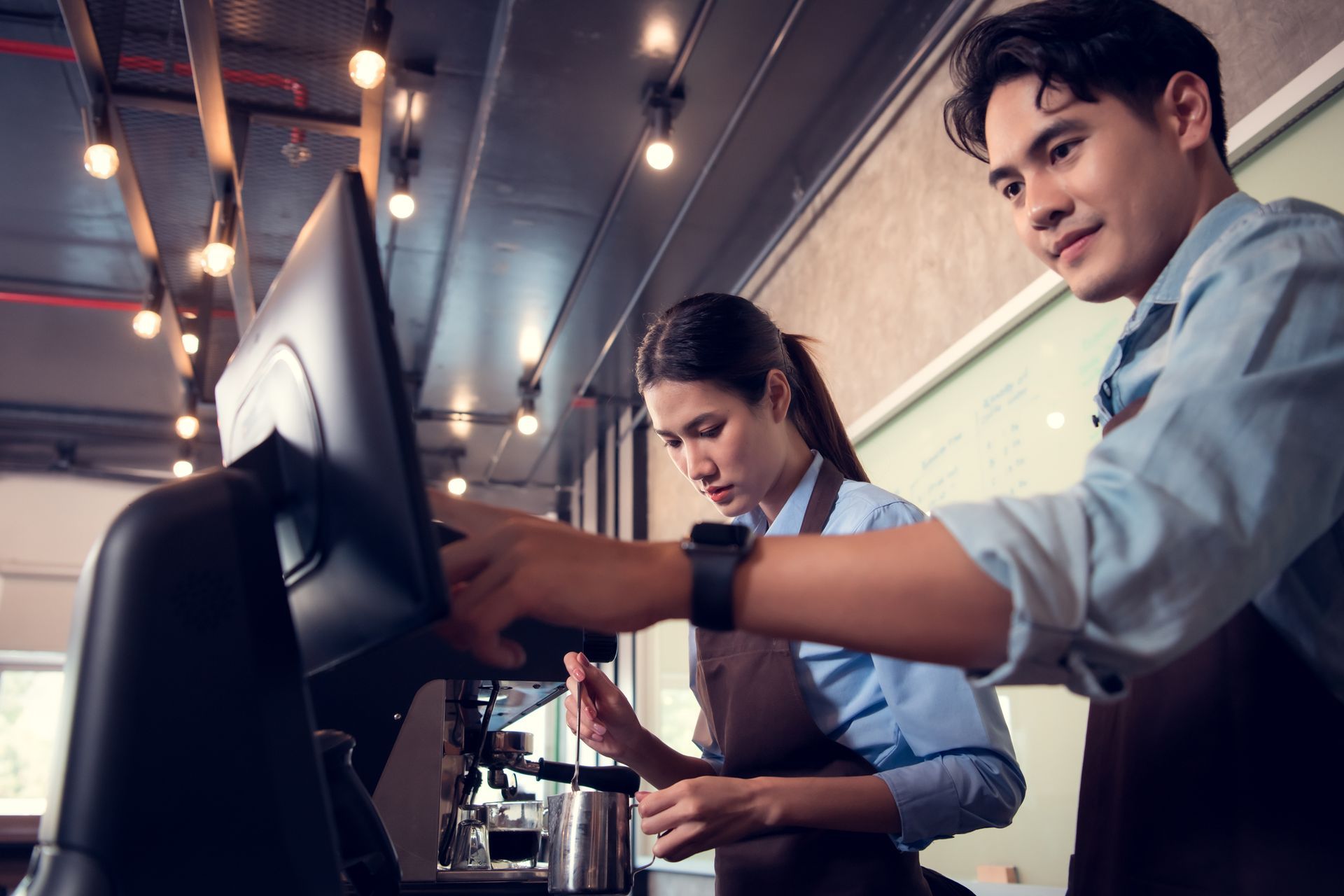 men and women at a coffee shop, checking customer out on the computer