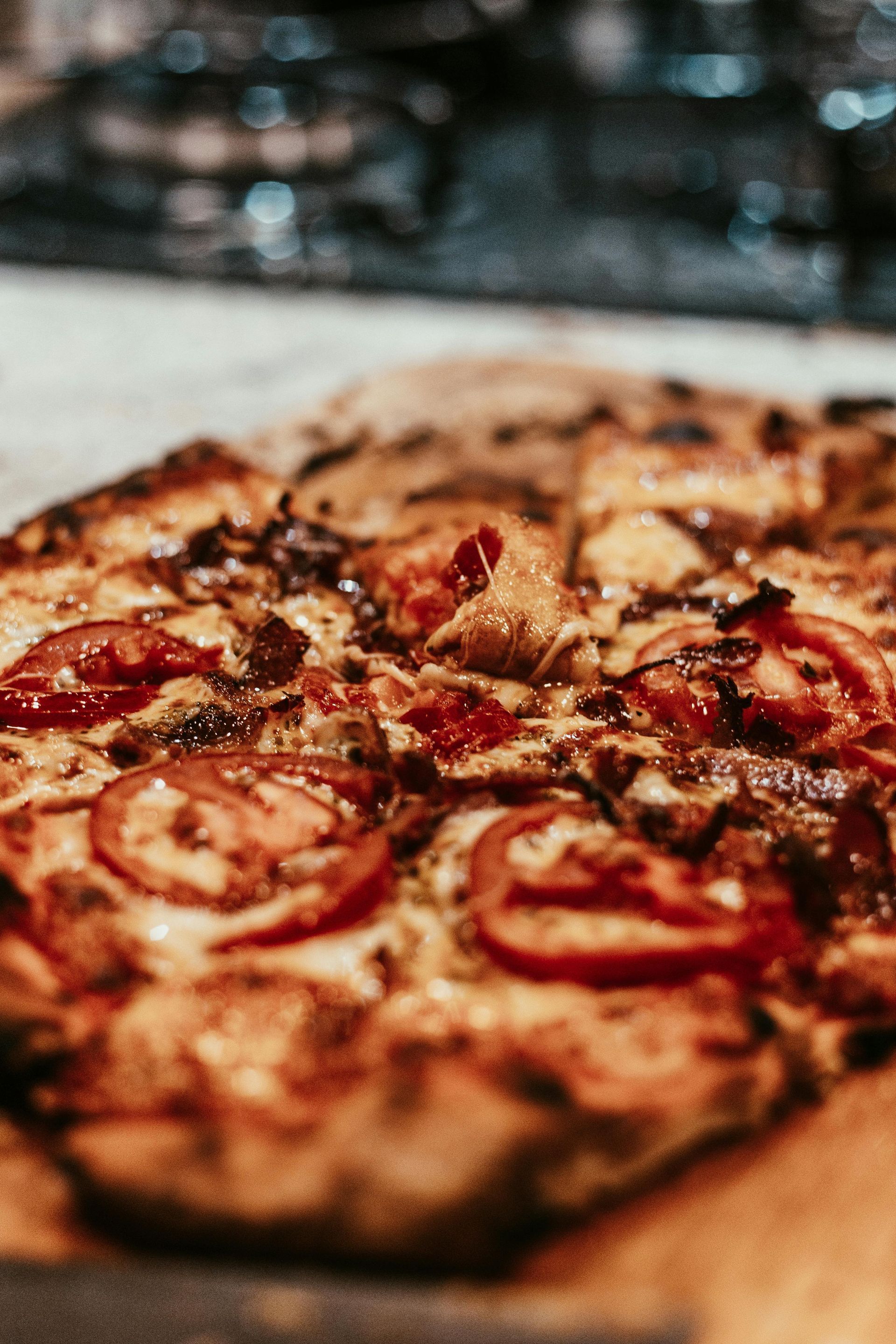 Close-up of a rustic pizza with pepperoni and herbs on a wooden board