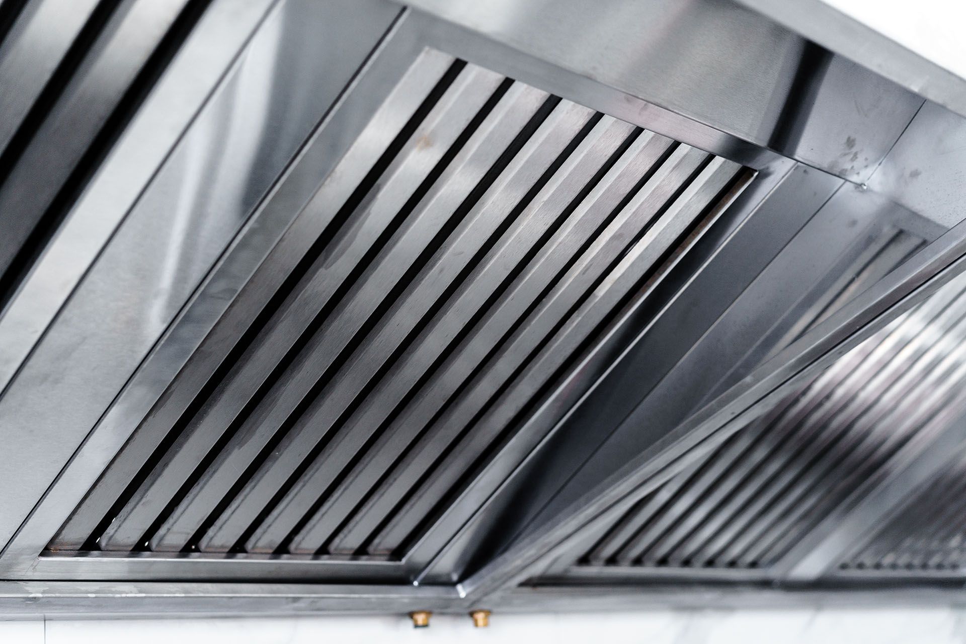 Clean stainless steel exhaust hood in professional kitchen.