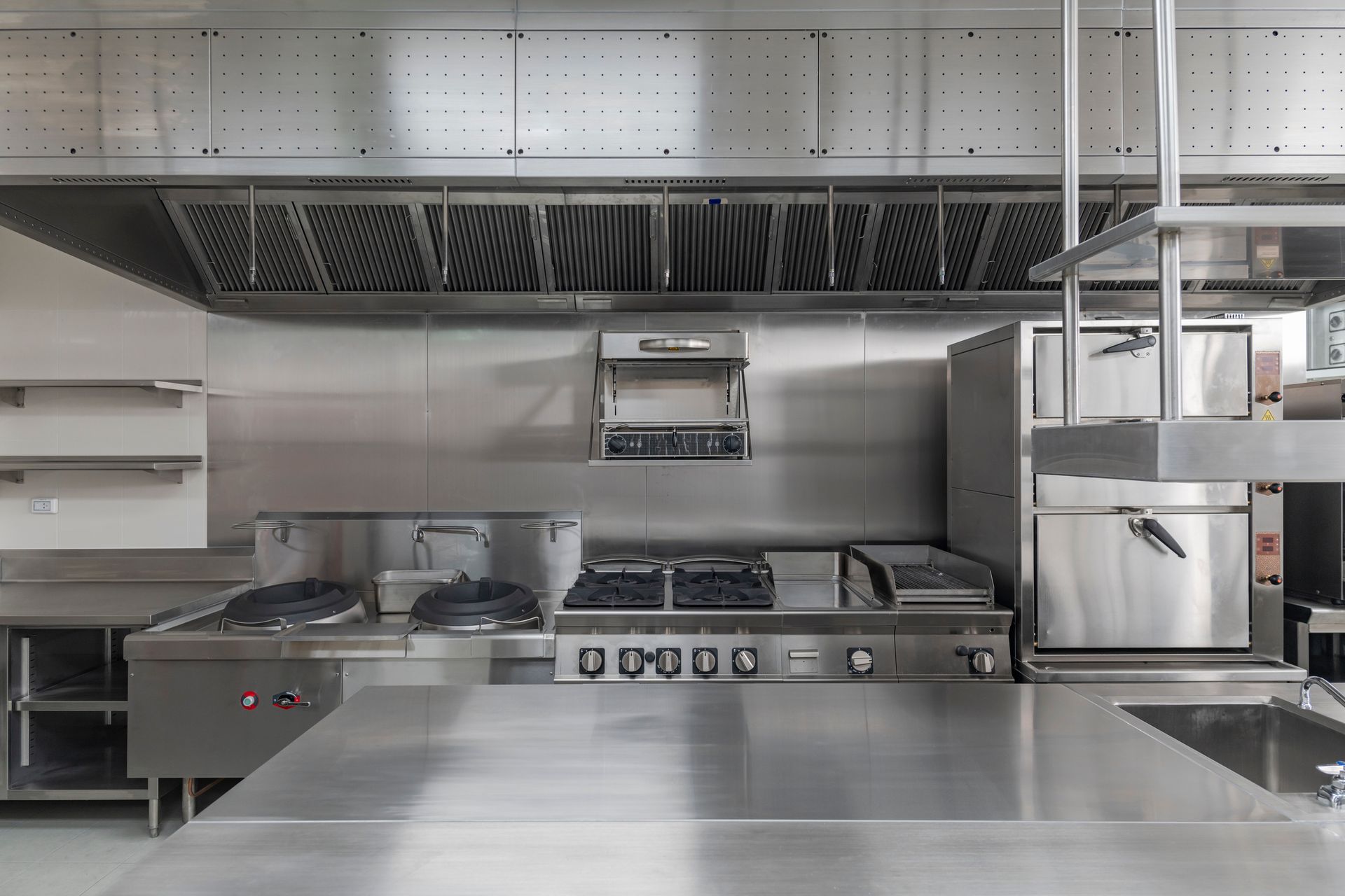 Modern commercial kitchen with stainless steel appliances and counters.