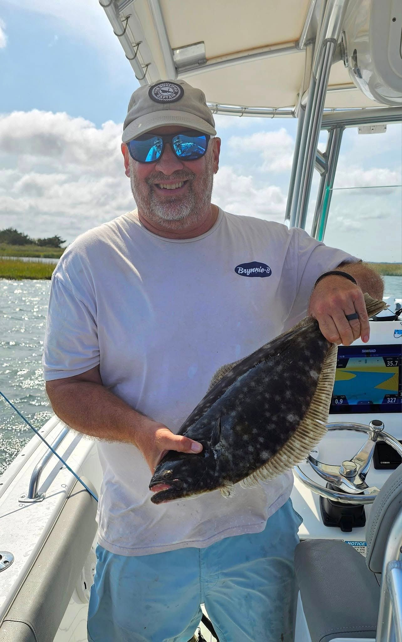 A man is holding a fish on a boat in the ocean.