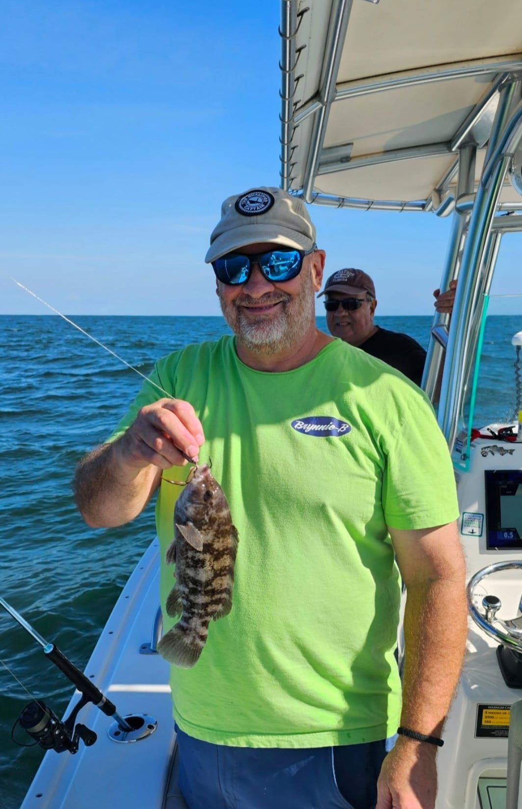 A man is holding a fish on a boat in the ocean.