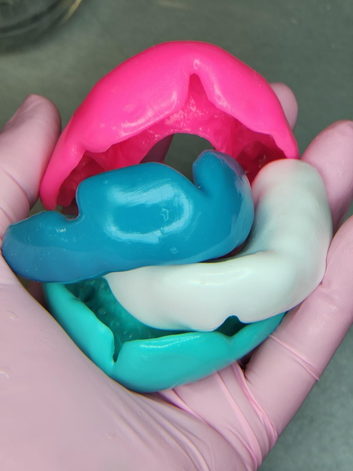 A Selection of Colourful Mouthguards Held in Hand — Goonellabah Denture Clinic In Goonellabah, NSW