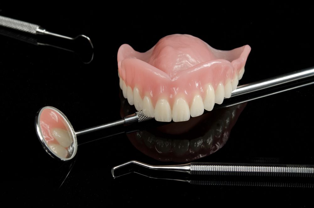 A Denture is Sitting on Top of a Dental Mirror — Goonellabah Denture Clinic in Bangalow, NSW