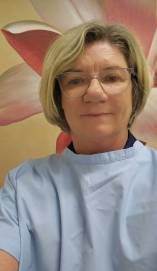 A Woman Wearing Glasses and a Blue Gown is Taking a Selfie — Goonellabah Denture Clinic in Goonellabah, NSW