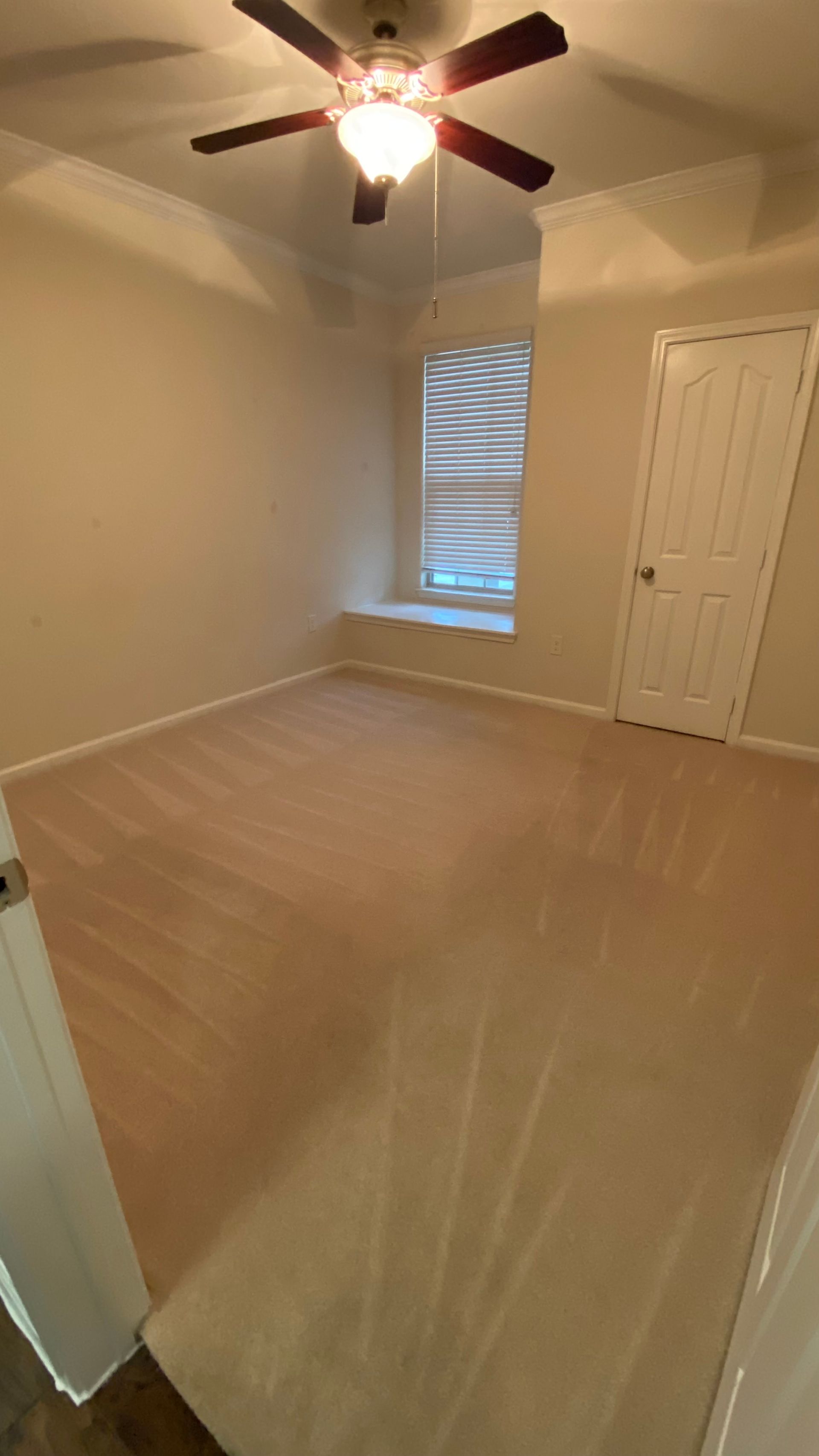 An empty bedroom with a ceiling fan and a window.