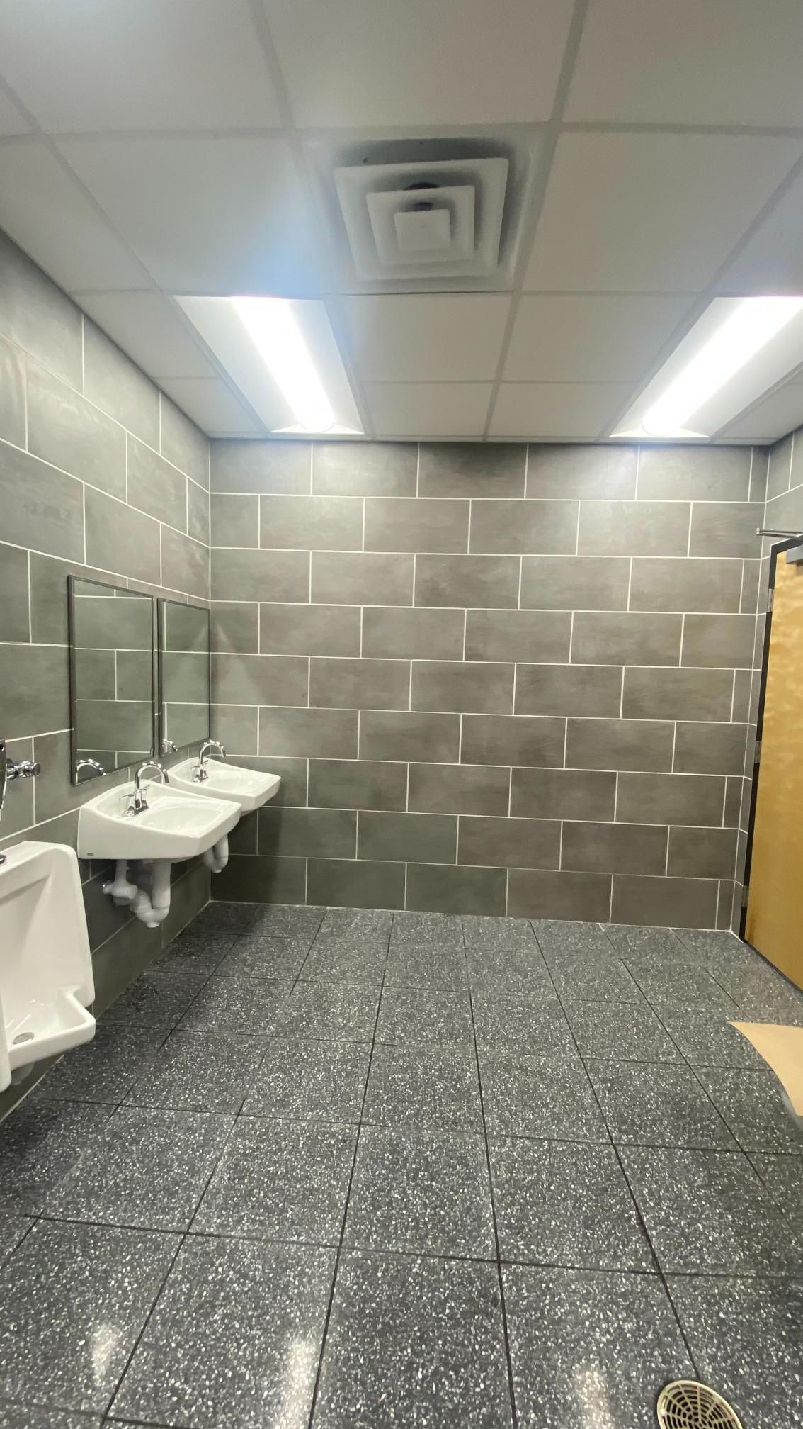 A bathroom with three sinks and two urinals.