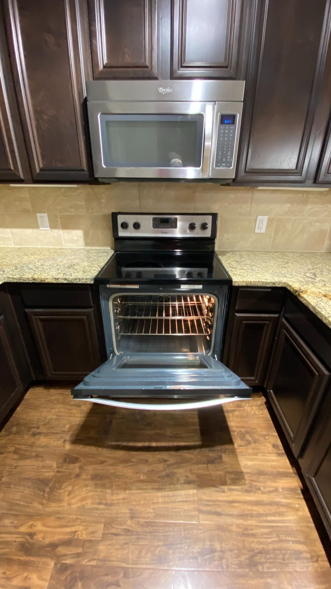 A kitchen with a stove , microwave , and oven with the door open.