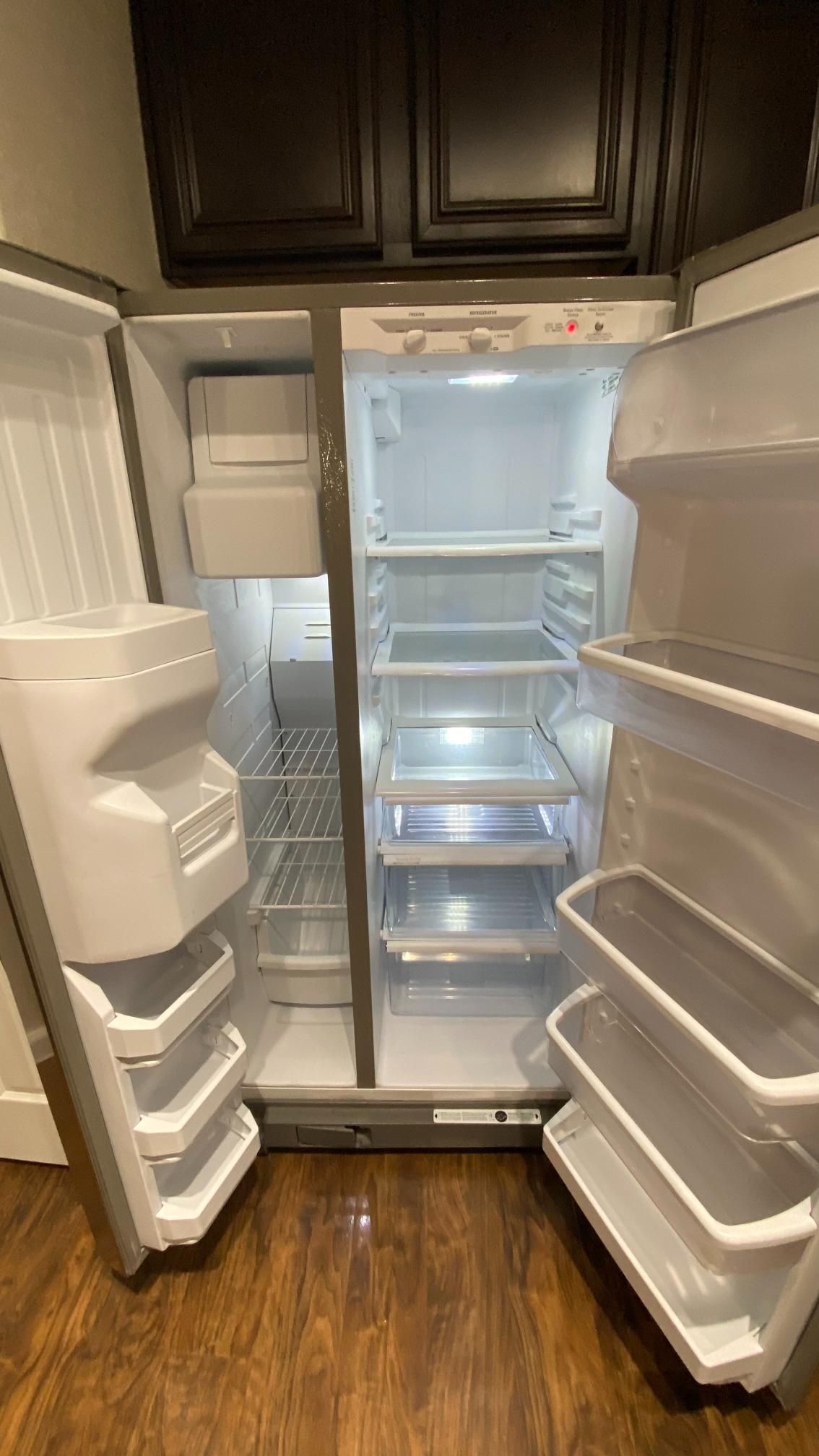 An empty refrigerator with the door open in a kitchen.
