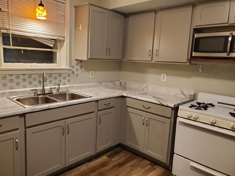 A kitchen with a sink , stove and microwave.
