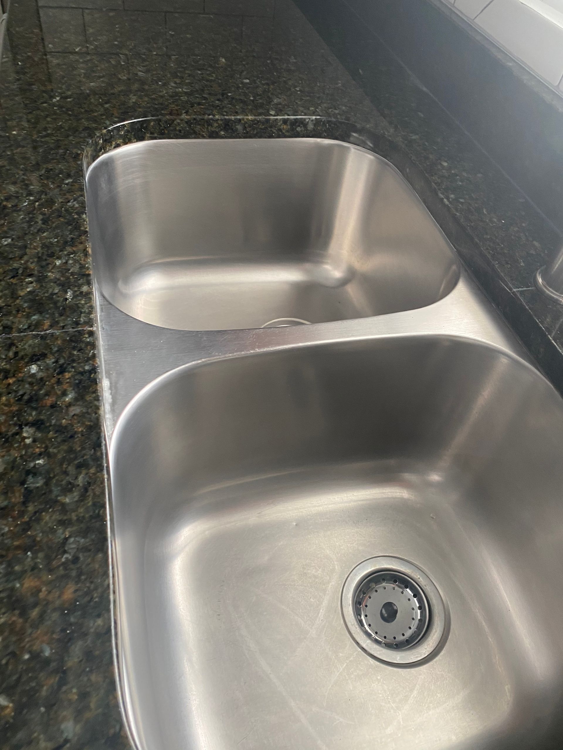 A stainless steel kitchen sink is sitting on top of a granite counter.