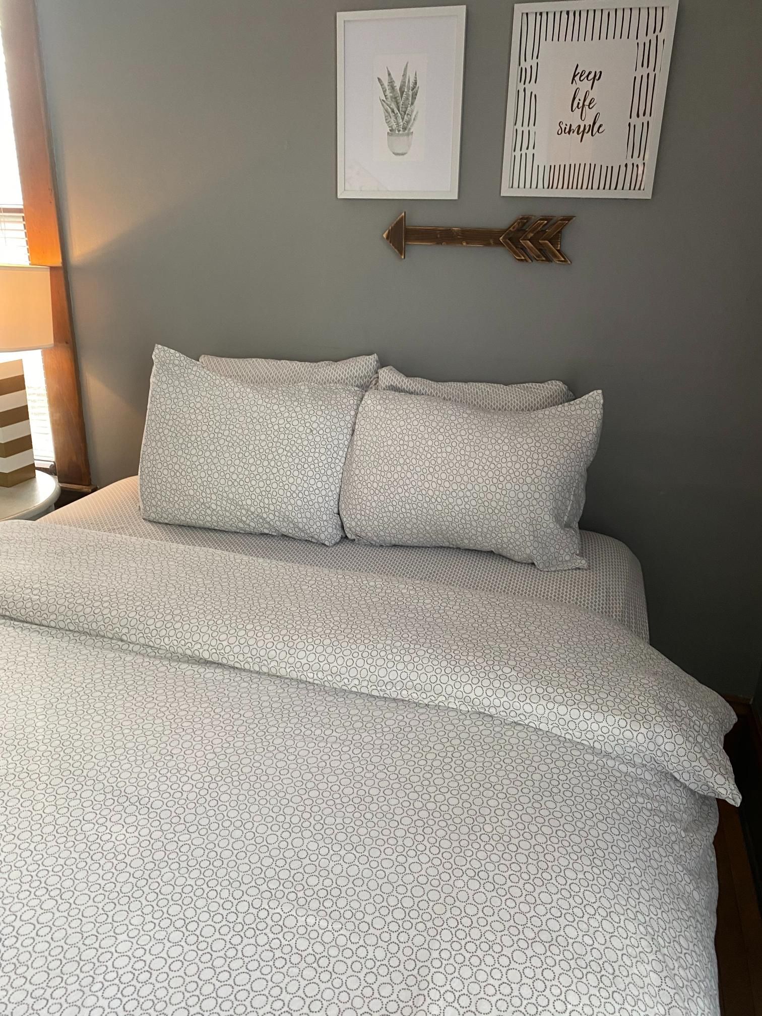 A bed with a white comforter and pillows in a bedroom.