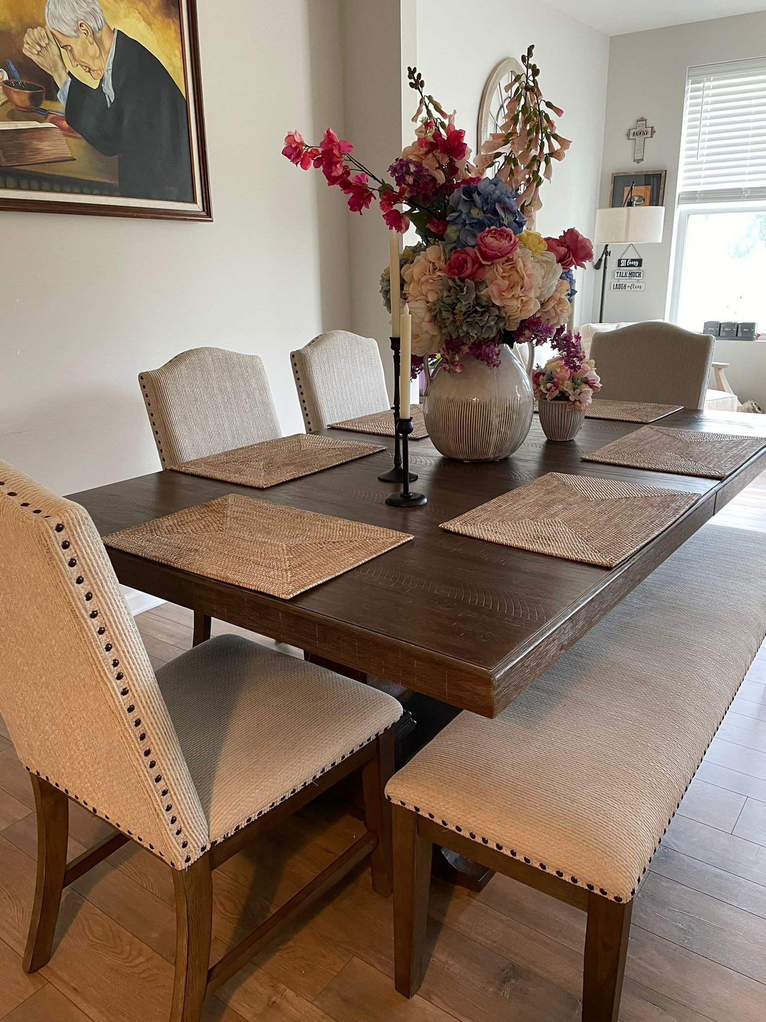 A dining room table and chairs with a vase of flowers on it.