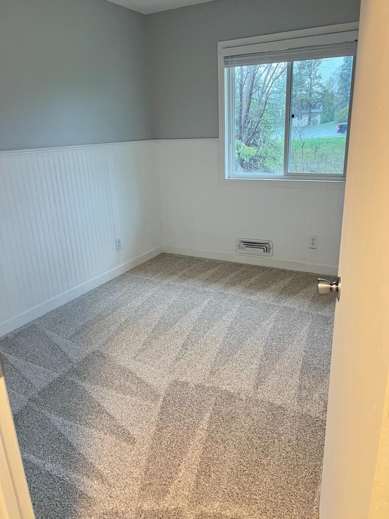 A bedroom with a carpeted floor and a window.