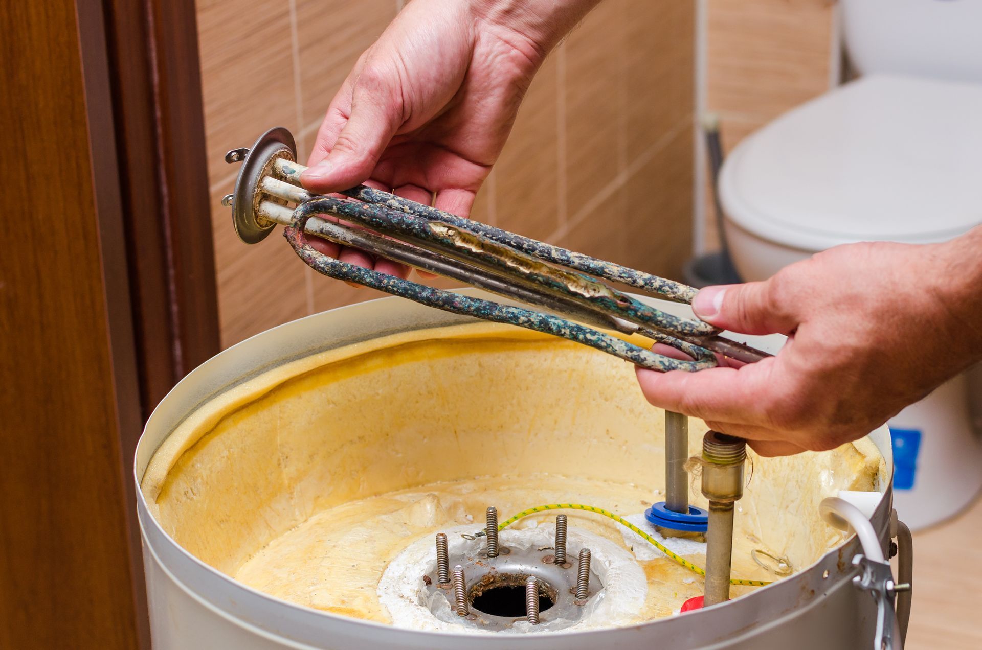 A person is fixing a water heater in a bathroom.