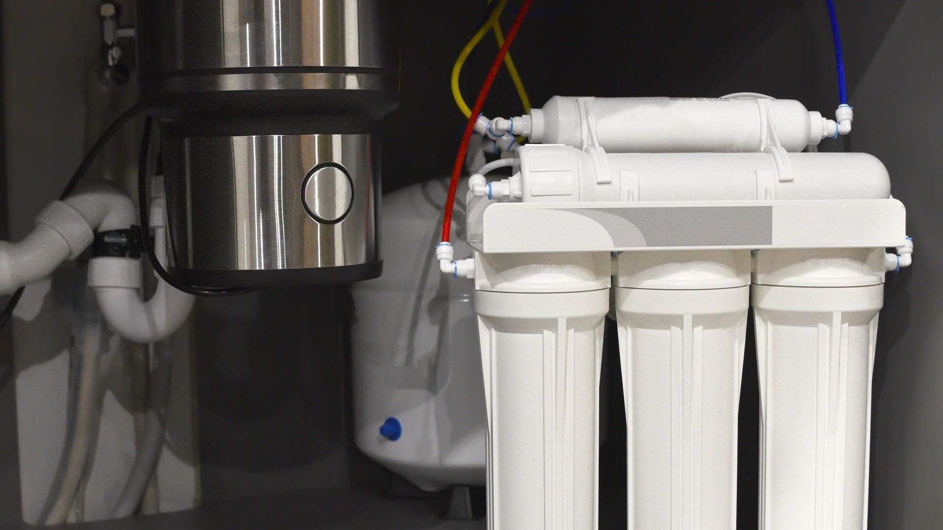 A water filter is sitting under a sink in a kitchen.