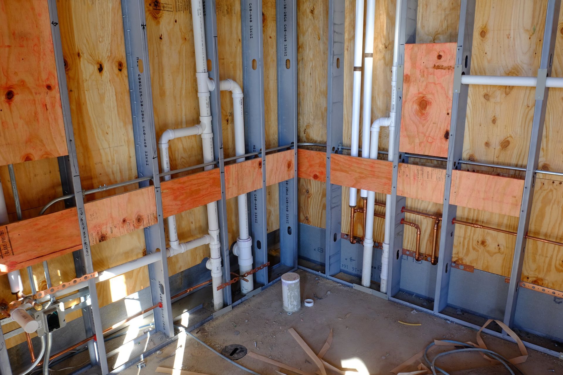 A bathroom under construction with pipes coming out of the walls.