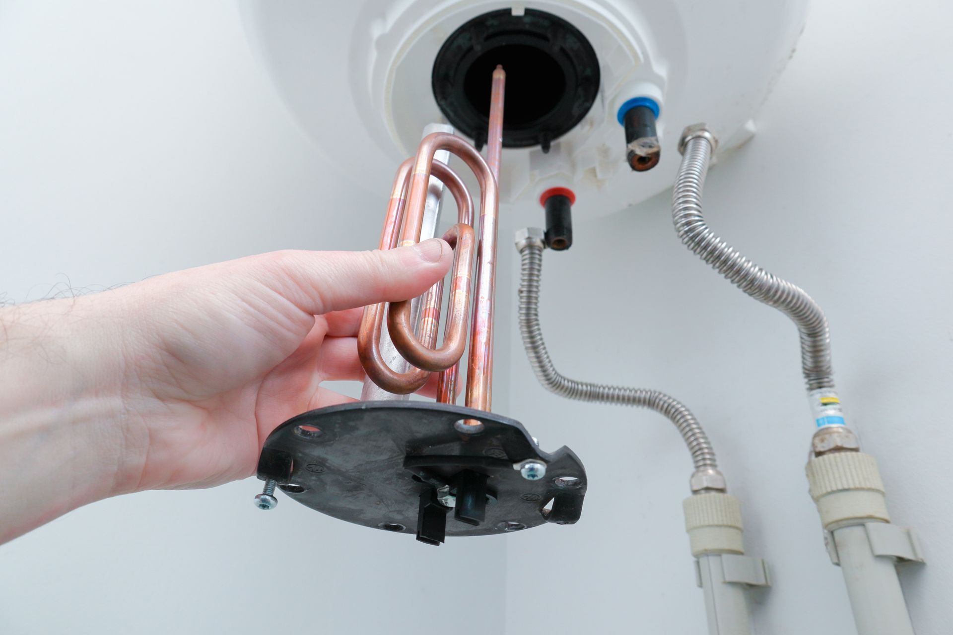 A person is fixing a water heater with a copper coil.