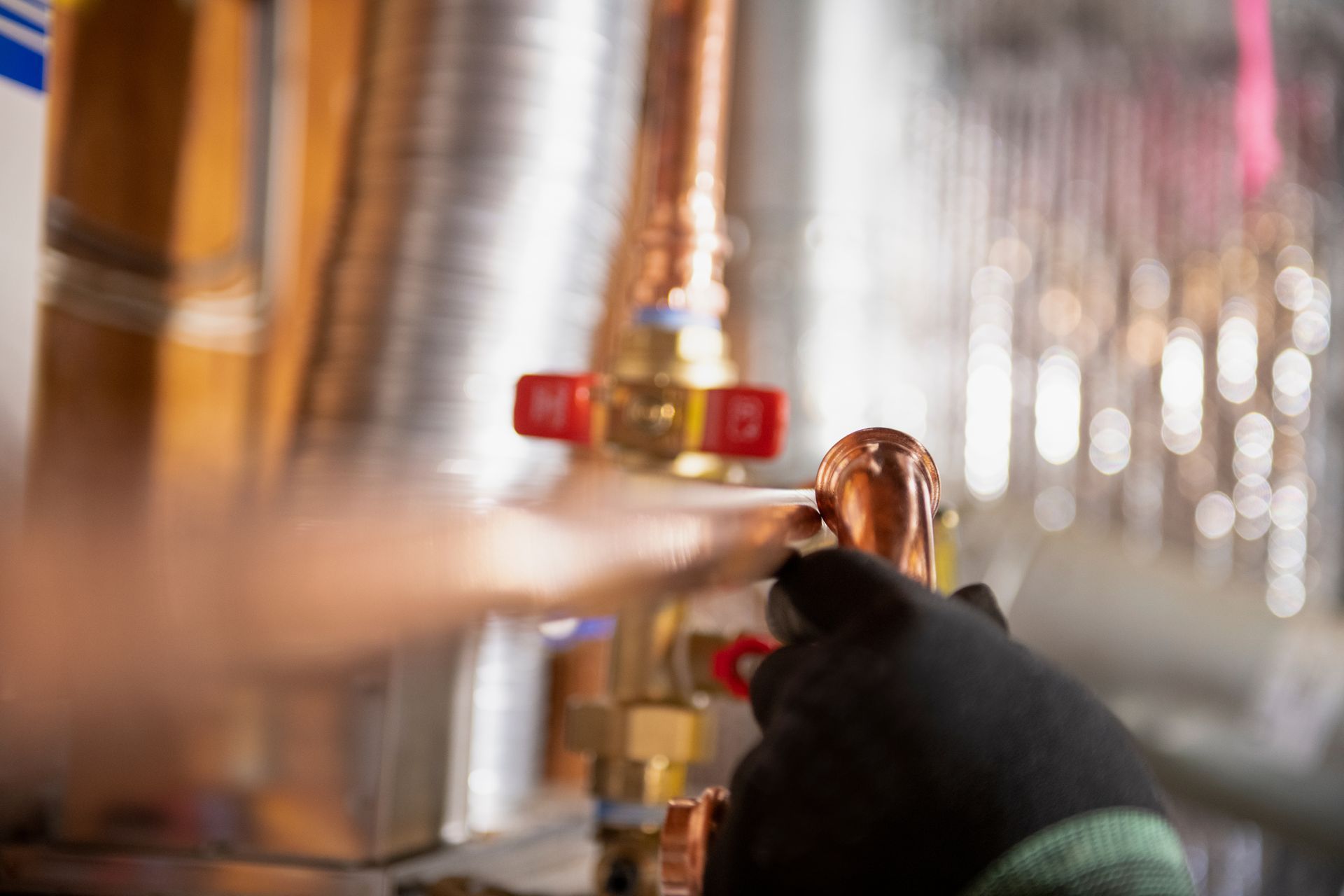 A person is working on a copper pipe with a wrench.
