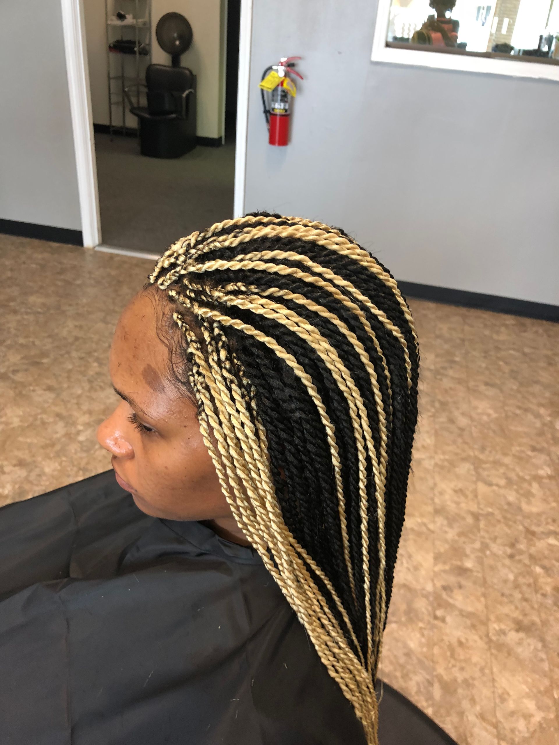 Woman with long black and blonde twist braids in a salon setting.