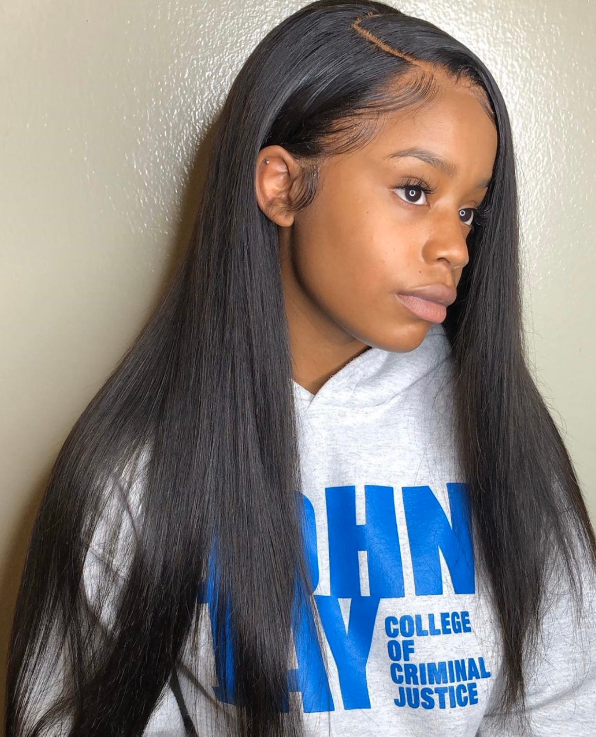 Woman with long, straight black hair, wearing a gray hoodie with blue text.