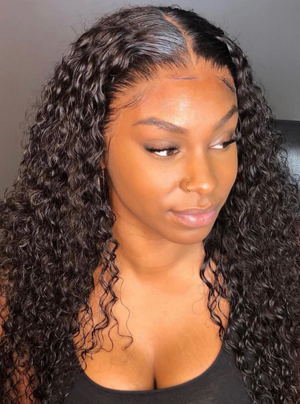 Woman with long, curly black hair, looking slightly to the side. She has brown skin and is wearing a black tank top.