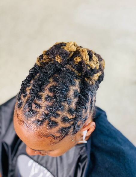 Woman with black and blonde locs styled up.