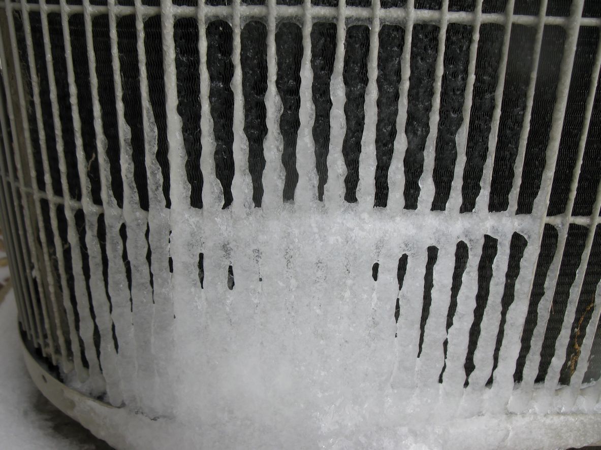 Close-up of an air conditioner unit with ice buildup on the coils.