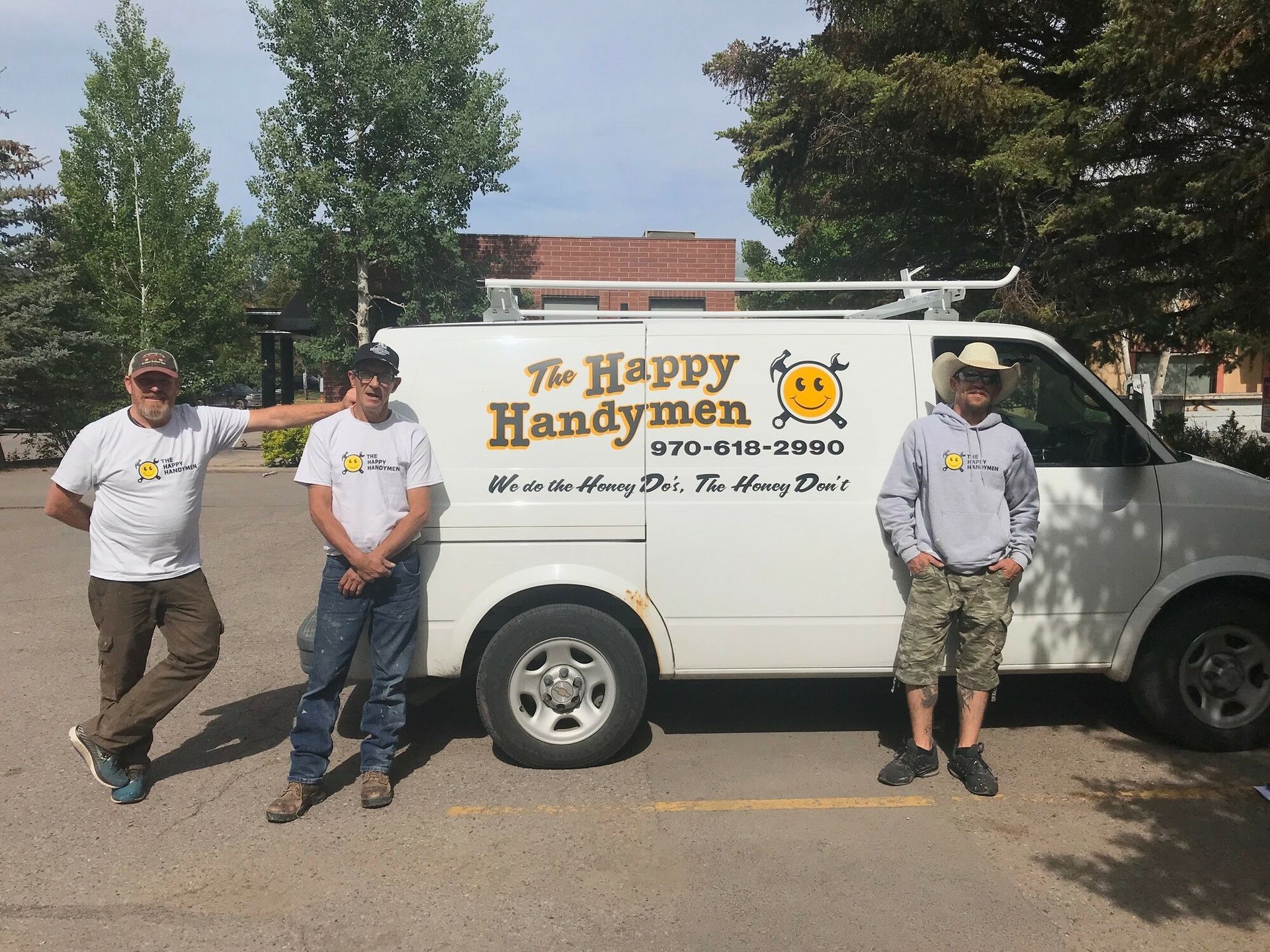 Three men standing in front of a white van that says the happy handymen