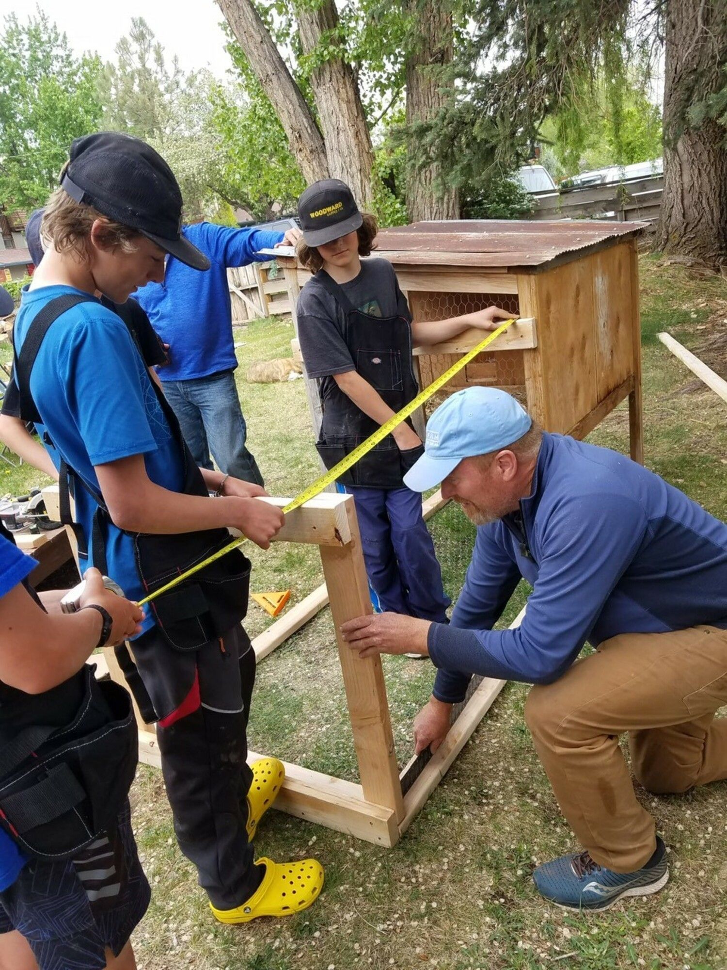 A group of people are measuring a piece of wood.