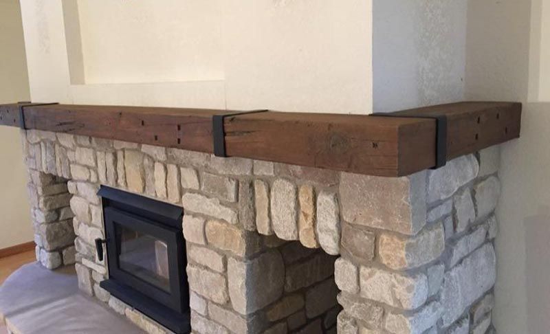 Stone fireplace with a dark wood mantel and black metal brackets.