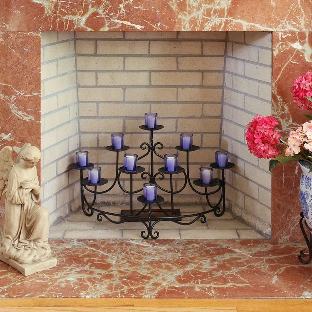 Candle holder with blue candles in a brick fireplace, flanked by angel statue and pink flowers.