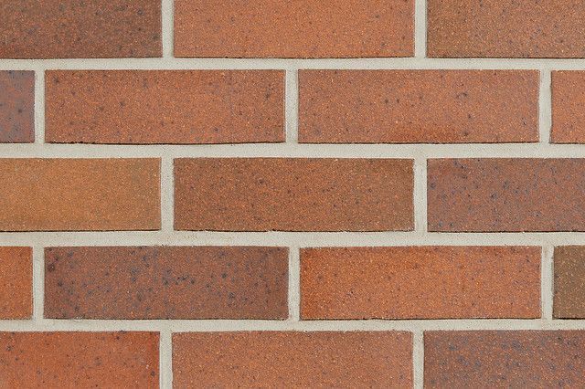 Brick wall with varied shades of red and brown bricks and white mortar.