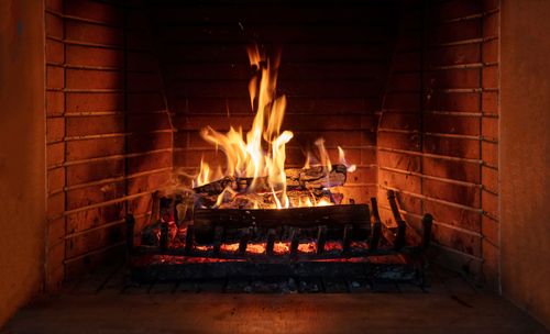 Fire burning in a brick fireplace; flames and glowing embers, warm orange light.