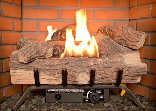 Gas fireplace with flames and artificial logs in a brick hearth.