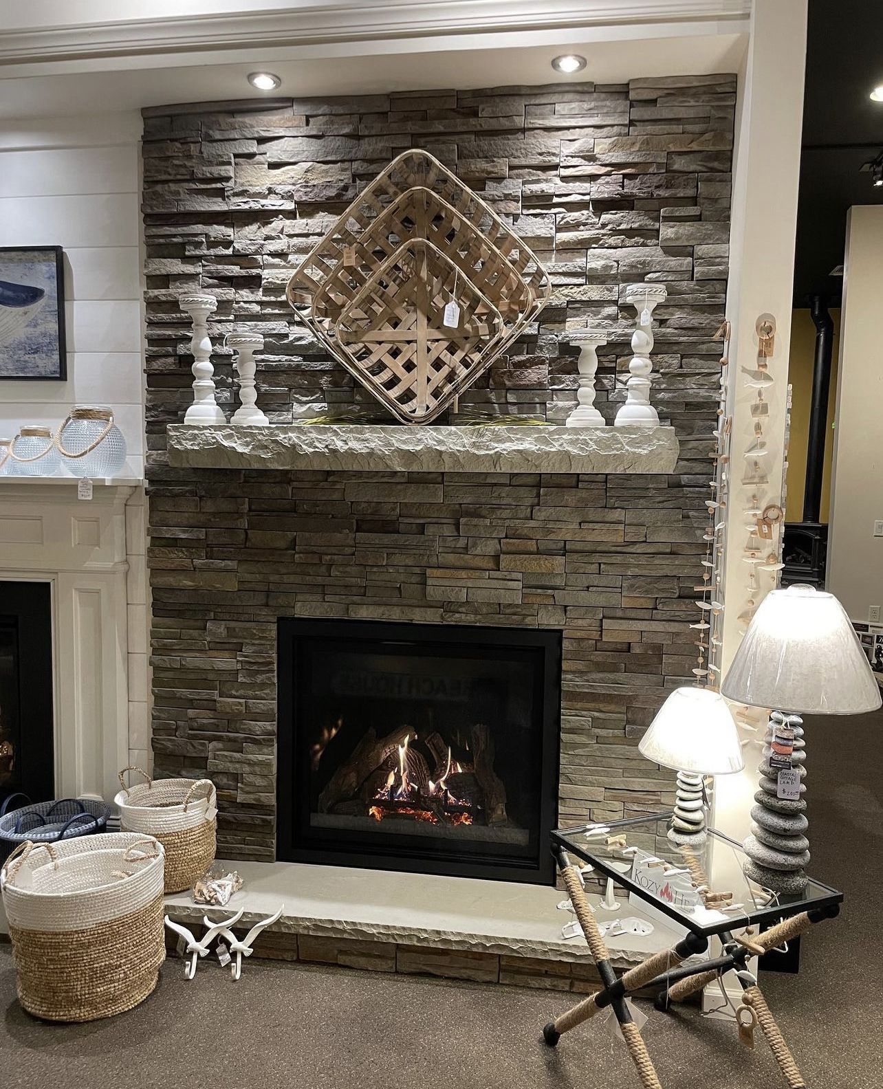 Fireplace with stone veneer, decorative shelf with candles, and wooden woven art.