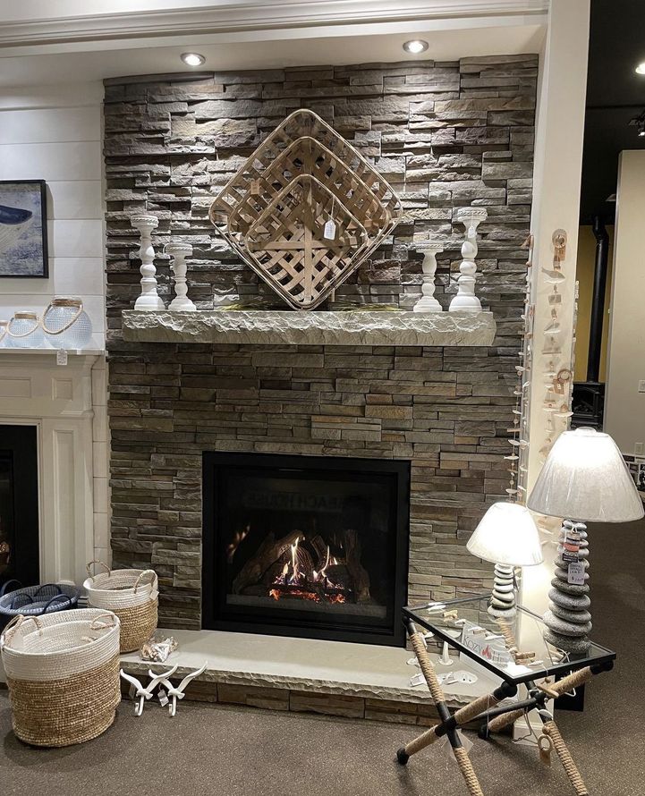 Fireplace with stone veneer, decorative shelf with candles, and wooden woven art.
