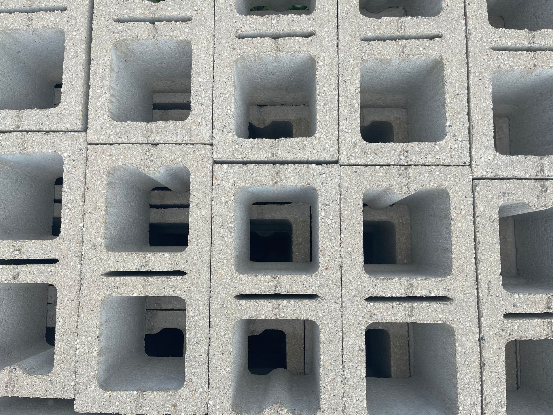 Stacked gray concrete breeze blocks with square openings.