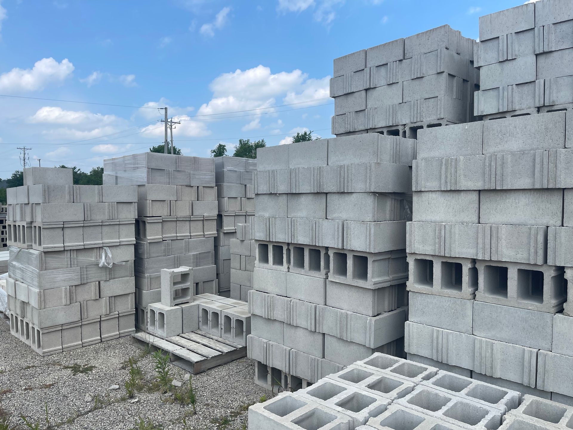 Stacks of gray concrete blocks at a construction site outdoors on a sunny day.