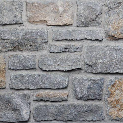 Gray and tan stone wall with gray mortar, rough-hewn texture.