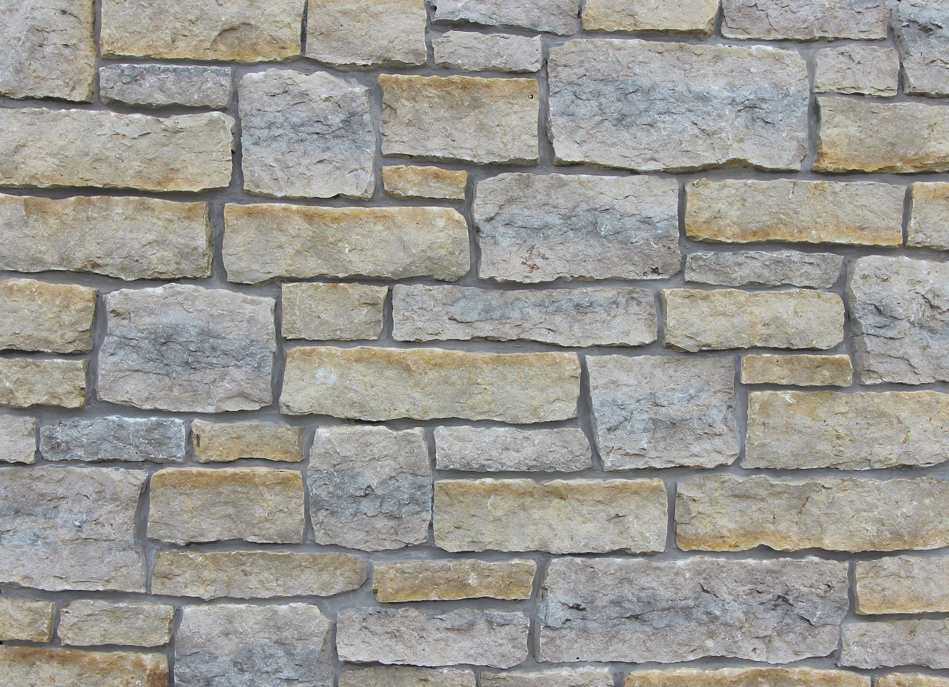 Stone wall made of rectangular beige and gray blocks.