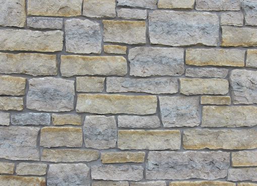 Stone wall made of rectangular beige and gray blocks.