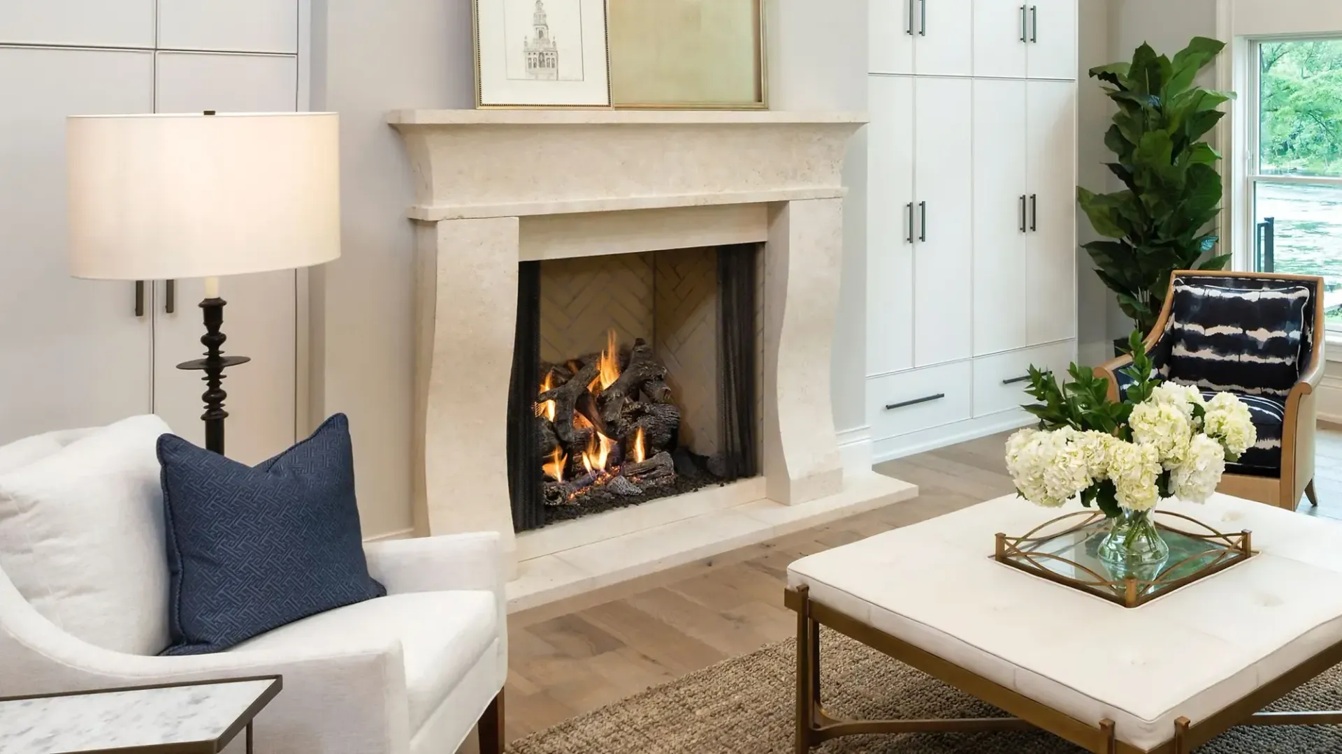 Living room with fireplace, white chairs, coffee table, and tall cabinets.
