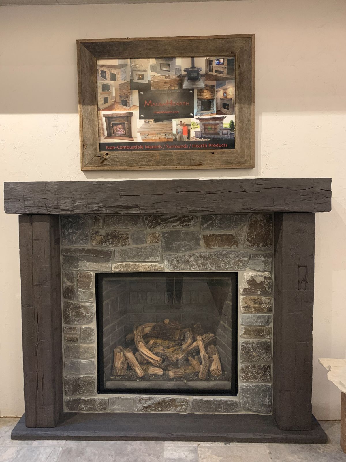 Fireplace with stone surround, dark wooden mantel and columns, and a collage above it.
