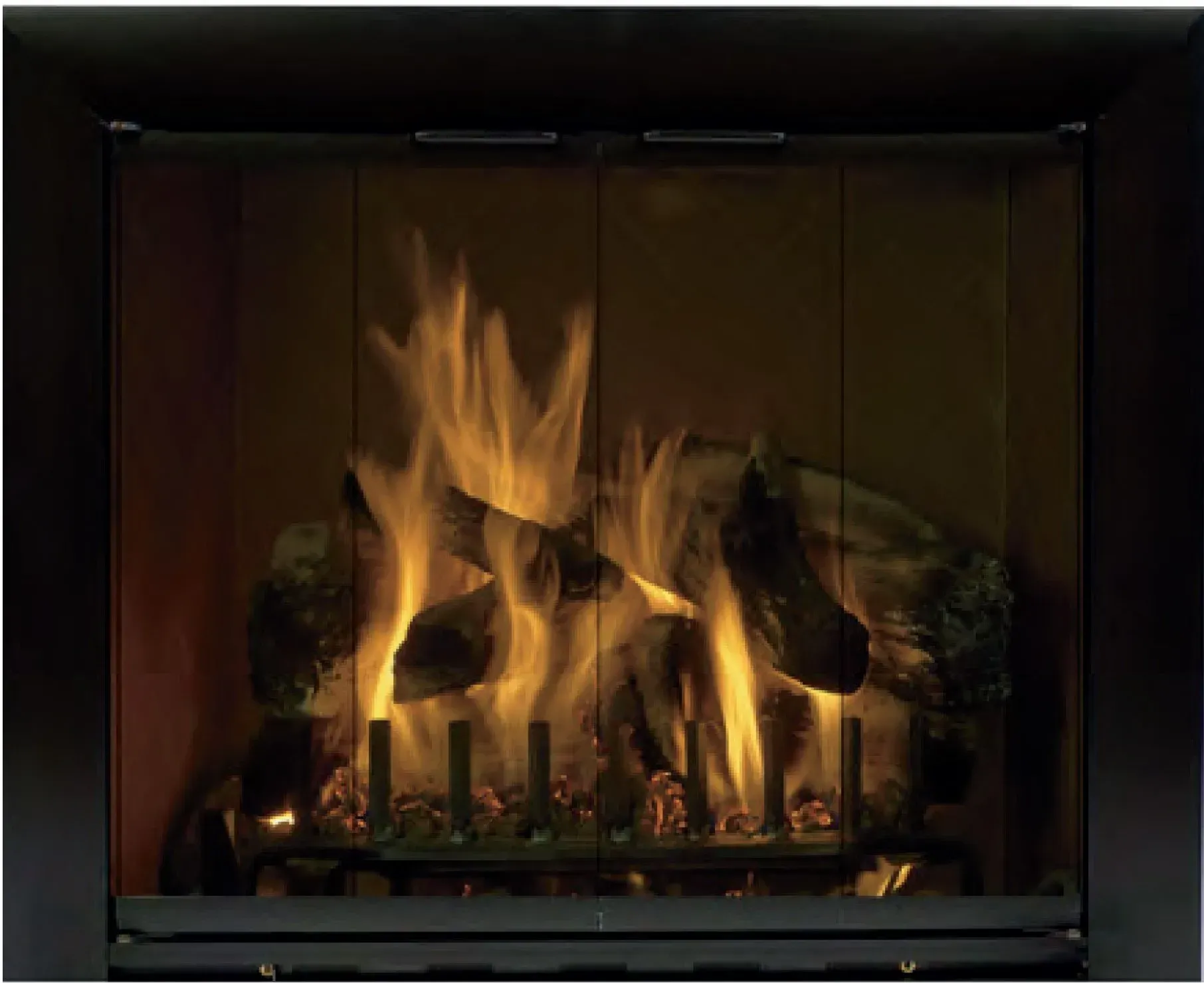 Burning fireplace with large orange flames behind glass doors and faux logs.