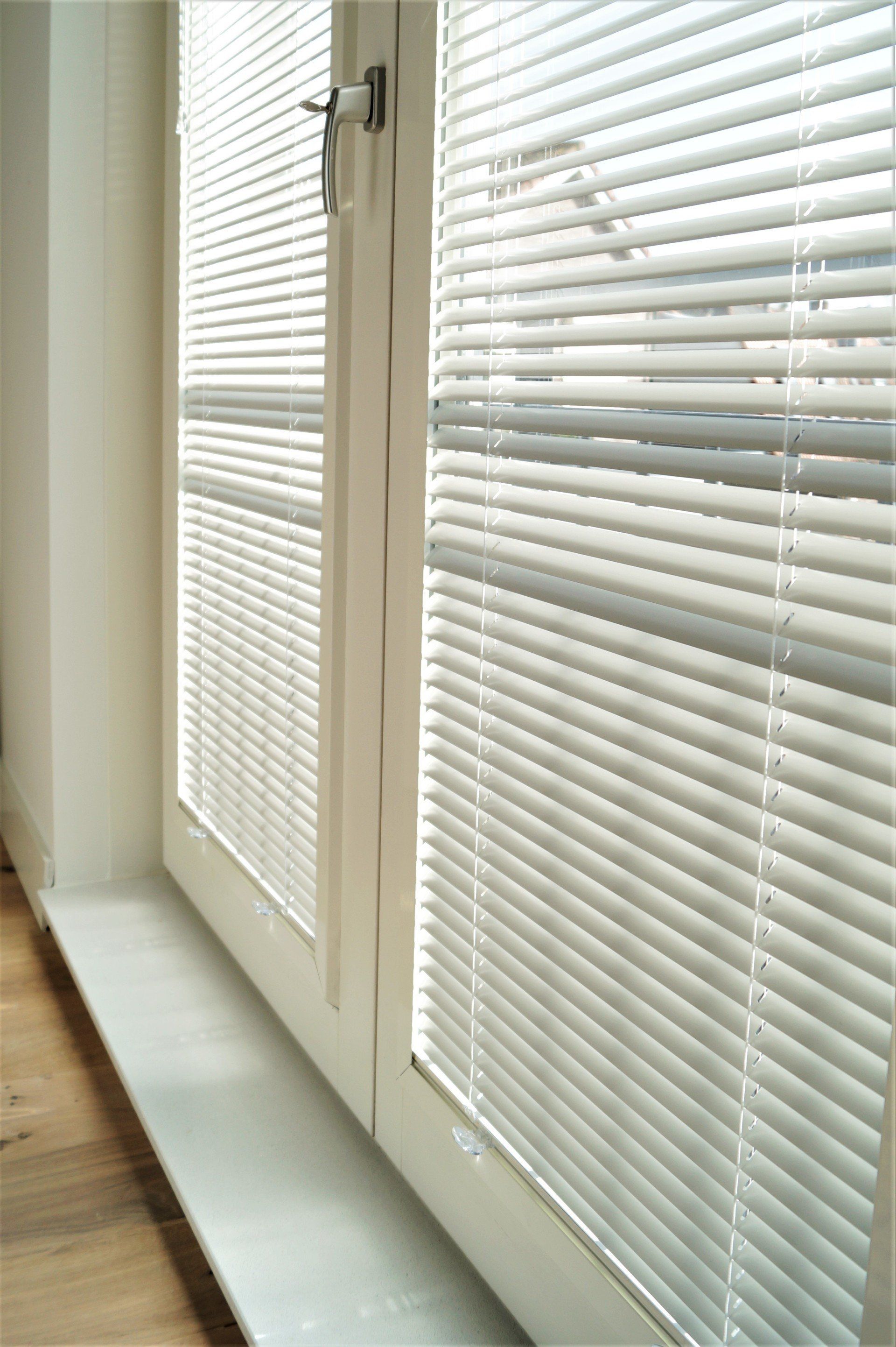 Witte jaloezieën in de slaapkamer.